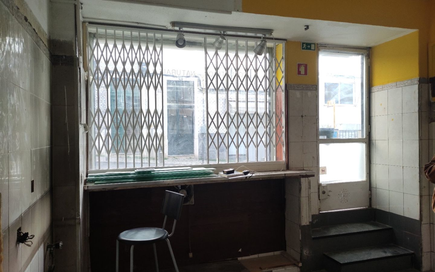 Antes: loja antiga com azulejos, grades e parede amarela