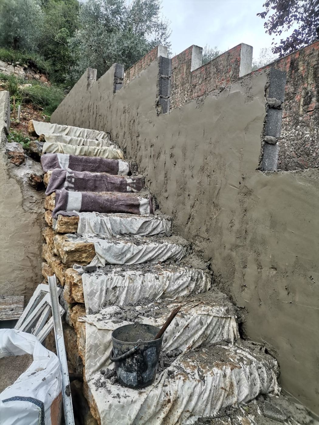 Escadaria em pedra junto a muro acabado de rebocar